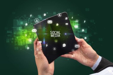 Sosyal medya yazıtları ve sosyal ağ konsepti olan katlanabilir bir akıllı telefon tutan bir iş adamı