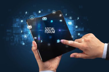 İş adamı elinde SOCIAL forum yazıtlı, sosyal ağ kavramlı katlanabilir bir akıllı telefon tutuyor.