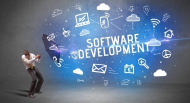 SOFTWARE DEVELOPMENT yazıtlarından şemsiyeyle savunma yapan iş adamı, modern teknoloji kavramı