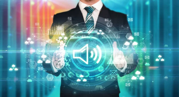 Businessman holding loud sound icon in his hands with multiple technology symbols around it