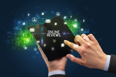 Online Reviews yazısını ve sosyal ağ kavramını içeren katlanabilir bir akıllı telefon tutan iş adamı