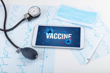 Beyaz yüzeyde VACCINE yazıtları, salgın konsepti olan tablet pc ve doktor araçları