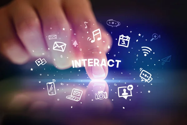 ソーシャルメディアのアイコンとInteract碑文 ソーシャルネットワークの概念を描いた指のタブレットに触れる — ストック写真