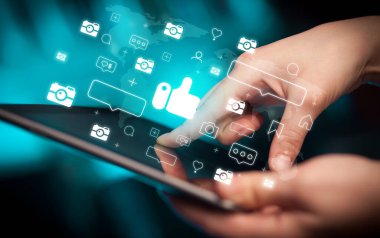 İçinden ikonlar çıkan tablet kullanan bir elin yakın plan resmi, sosyal medya kavramı