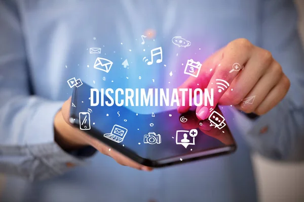 Adamı Elinde Katlanabilir Bir Akıllı Telefon Tutuyor Üzerinde Discrimination Yazıtları — Stok fotoğraf