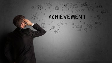 İş adamı, ACHIEvEMENT yazıtları ve iş stratejisi konseptiyle yaratıcı bir fikir çizimi yapıyor.