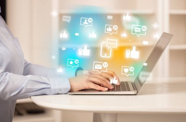 Akıllı telefon sohbet ikonları ve sosyal medya konseptiyle dizüstü bilgisayarda sörf yapan genç kişi