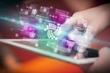 Tablet kullanan bir elin yakın plan resmi, tabletten çıkan iota simgeleri, dijital para birimi konsepti