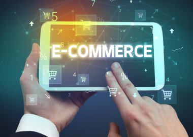 E-COMERCE yazıtları ve online alışveriş konseptiyle el ele tutuşan tabletin yakın çekimi