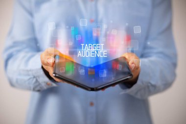 Katlanabilir bir akıllı telefon tutan genç adam TARGet AUDIENCE yazıtları, eğitim konsepti