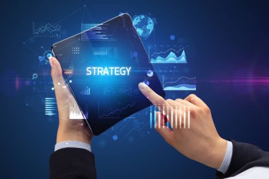 İş adamı elinde Strateji yazıtlı, başarılı bir iş konsepti olan katlanabilir bir akıllı telefon tutuyor.