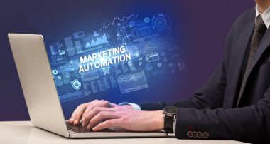 MARKETING AUTOMATION yazıtları, siber teknoloji kavramı ile birlikte dizüstü bilgisayarda çalışan bir işadamı