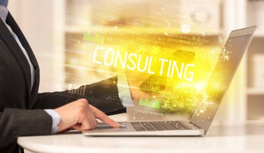 CONSULTING yazıtları ve başarılı iş konsepti ile birlikte dizüstü bilgisayarda çalışan iş adamlarının yakınlaşması