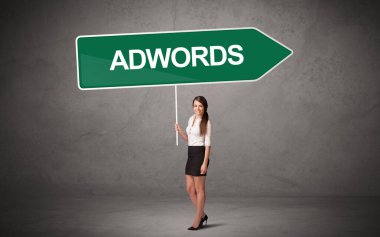 Üzerinde ADWORDS yazıları, yeni iş yönü konsepti olan günlük bekleme yolu tabelasında genç bir iş adamı