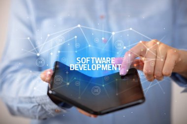 İş adamı elinde SOFTWARE DEVELOPMENT yazıtlı katlanabilir bir akıllı telefon tutuyor, yeni teknoloji konsepti