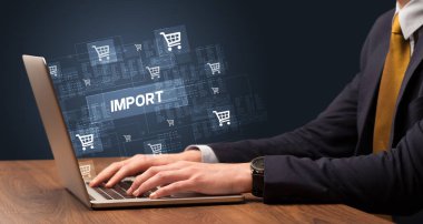 IMPORT yazıtları ve online alışveriş konseptiyle birlikte dizüstü bilgisayarda çalışan bir işadamı