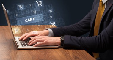 CART yazıtları ve online alışveriş konseptiyle birlikte dizüstü bilgisayarda çalışan bir işadamı