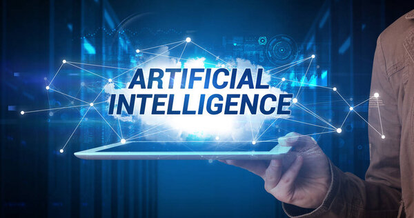Young business person working on tablet and shows the inscription: ARTIFICIAL INTELLIGENCE