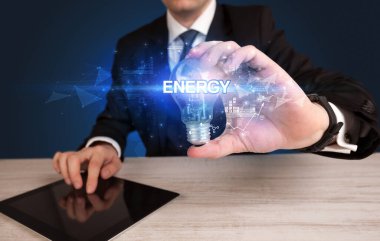ENERGY yazıtlı, yenilikçi teknoloji kavramına sahip bir iş adamı elinde ampul tutuyor