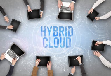 HYBRID CLOUD insciption, web güvenlik kavramı olan bir dizüstü bilgisayarın önünde bir grup insan