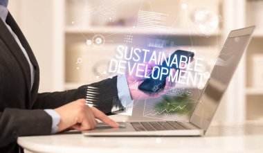 Diz üstü bilgisayarda çalışan bir iş adamının yan görünüşü SuSTAINable DEVELOPMENT yazıtları, modern iş konsepti