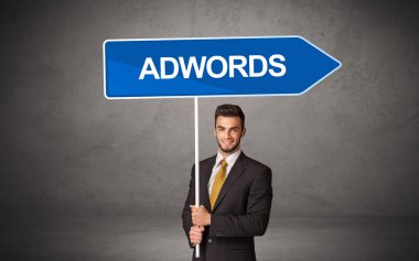 Üzerinde ADWORDS yazıları, yeni iş yönü konsepti olan günlük bekleme yolu tabelasında genç bir iş adamı
