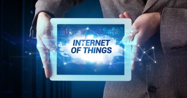 Tablet üzerinde çalışan genç iş adamı ve yazıtı gösteriyor: Nesnelerin İnterneti