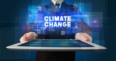 Tablet üzerinde çalışan genç iş adamı ve yazıyı gösteriyor: İklim değişikliği