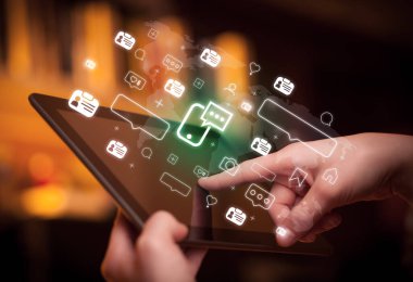 Akıllı telefon sohbet simgeleri içeren tablet kullanan bir elin yakın çekimi, sosyal medya kavramı
