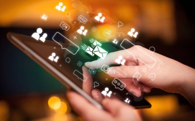 Mesajlaşma simgeleri içeren tablet kullanan bir elin yakın plan görüntüsü, sosyal medya kavramı