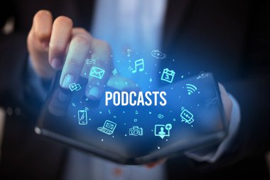 Podcast yazıları ve sosyal medya konsepti olan katlanabilir bir akıllı telefon tutan bir iş adamı