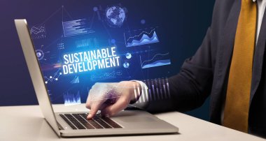 Sürdürülebilir Kalkınma yazıtları ve yeni iş kavramı ile dizüstü bilgisayarda çalışan işadamı