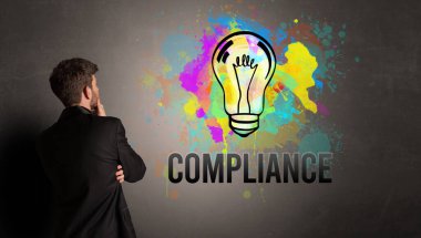 İşadamı desenli beton duvara COMPLIANCE yazısıyla renkli ampul çiziyor, yeni iş fikri kavramı