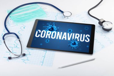 Beyaz yüzeyde CORONAVIRUS yazıtı, salgın konsepti içeren tablet pc ve doktor araçları