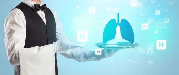 Handsome young waiter in tuxedo holding tray with lungs icons on tray, global healthcare concept