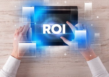 ROI kısaltması ile el ele tutuşma tableti, modern teknoloji konsepti