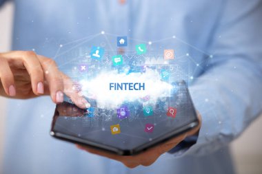 FINTECH yazıtlı, teknoloji konseptli katlanabilir bir akıllı telefon tutan bir iş adamı