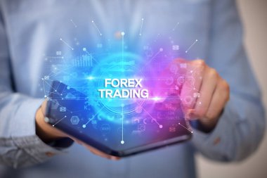 İş adamı elinde FOREX TRADING yazıtları ve yeni iş konseptiyle katlanabilir bir akıllı telefon tutuyor.