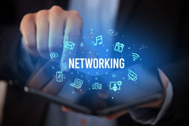 İş adamı elinde NETworking yazıtlı, sosyal medya kavramlı katlanabilir bir akıllı telefon tutuyor.