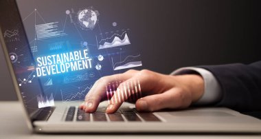 Sürdürülebilir Kalkınma yazıtları ve yeni iş kavramı ile dizüstü bilgisayarda çalışan işadamı