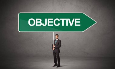 OBJECTIVE yazıtları, yeni iş yönü kavramı ile günlük bekleme yolu tabelasında genç iş adamı