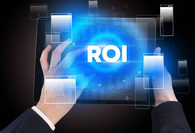 ROI kısaltması ile el ele tutuşma tableti, modern teknoloji konsepti