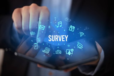İş adamı elinde katlanabilir bir akıllı telefon tutuyor. Üzerinde SURVEY yazıları, sosyal medya kavramı var.