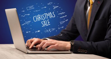 Diz üstü bilgisayarında çalışan işadamı. Noel Satışı yazıtları, online alışveriş danışmanları.