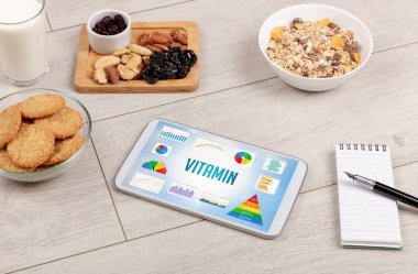 Organik gıda ve tablet bilgisayarı VITAMIN yazısını, sağlıklı beslenme bileşimini gösteriyor