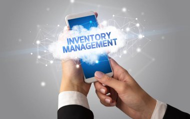 Dişi el akıllı telefona dokunuyor InVENTORY MANAGEMENT yazıtları, bulut iş konsepti