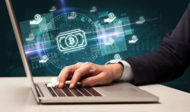 Borsada çalışan iş adamı dizüstü bilgisayardan çıkan bitcoin para simgeleriyle