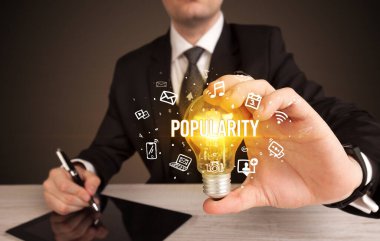 Popülerlik yazıtı ve sosyal medya kavramına sahip bir iş adamı elinde ampul tutuyor