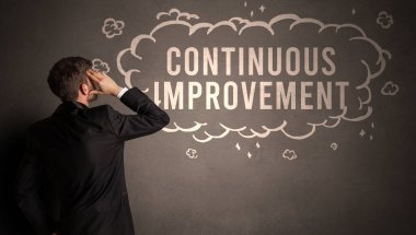 İş adamı içinde KONTINUOUS İMPROVEMENT yazıtları olan bir bulut çiziyor, modern iş konsepti
