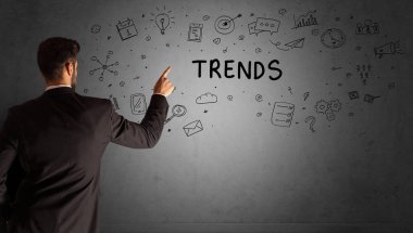 İş adamı, TRENDS yazıtları ve iş stratejisi konseptiyle yaratıcı bir fikir çizimi yapıyor.